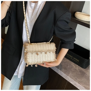 Détail du sac bandoulière en paille avec franges de coquillages et chaîne dorée
