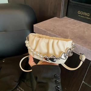 Chic cream ruched dumpling bag with pearl and silver heart handle held in hand