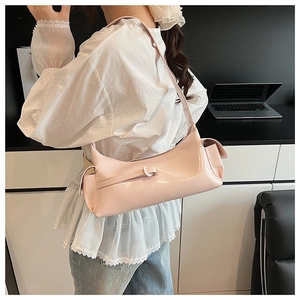 Détail d'un sac baguette rose clair brillant avec poches latérales et boucle décorative