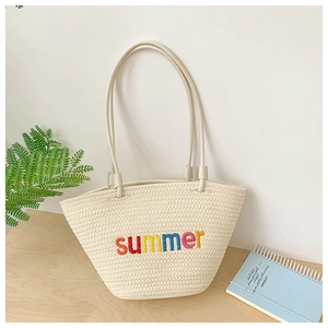 Detail of hand-woven beige tote bag featuring colorful summer embroidery and slim straps