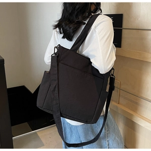 Detail of a black versatile tote bag showing adjustable shoulder strap and side pockets
