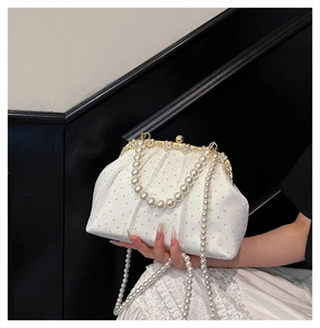 Gros plan du sac de soirée en tissu plissé blanc avec poignée perle et fermoir doré