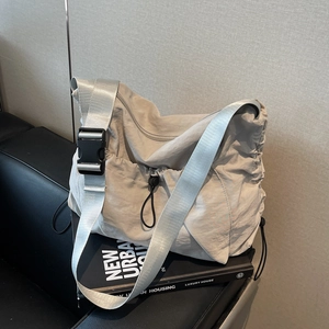 Minimalist beige nylon dumpling bag with adjustable wide shoulder strap and black buckle