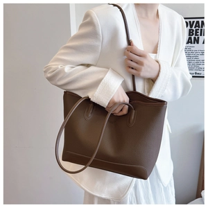 Detail of dark brown pebble leather tote bag with fine texture and slim shoulder straps