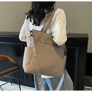 Close-up of khaki canvas tote bag featuring adjustable strap and durable metal buckles
