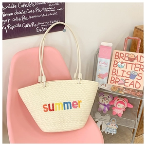 Close-up of summer embroidered woven tote bag with colorful letters on beige texture