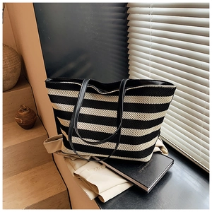 Detail of black and white striped woven tote bag with leather straps in a cozy room