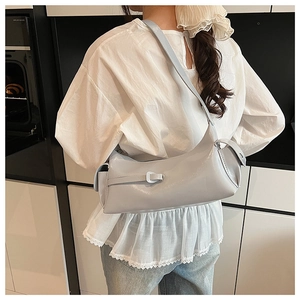 Detail of light blue faux leather baguette bag with metal buckle and shoulder strap