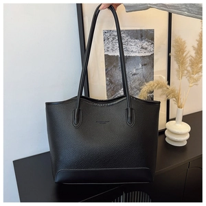 Close-up of black leather tote bag with FASHION & BAGS embossing and pebble texture