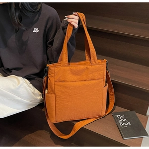 Detail of a large caramel canvas tote bag showing handle and adjustable strap in scene