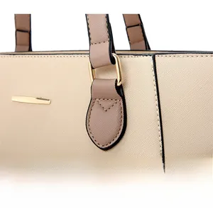 Reinforced handle detail of beige Saffiano leather tote with gold metal hardware