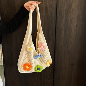 Sac en tricot beige avec fleurs au crochet colorées et bandoulière sur fond en bois