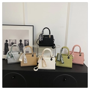 Detail of square handbags in six colors with woven handles and silk scarf accents