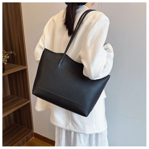 Detail of black tote bag with litchi texture showing slim shoulder straps and large capacity