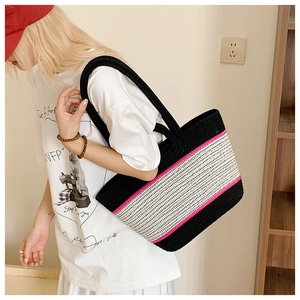 Detail of hand-woven tote bag with contrast stitching and cylindrical black woven handles