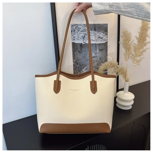 Close-up of cream and brown tote bag showing textured leather and fashion branding