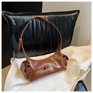 Detail of a brown glossy leather shoulder bag with side buckle pocket and zipper closure