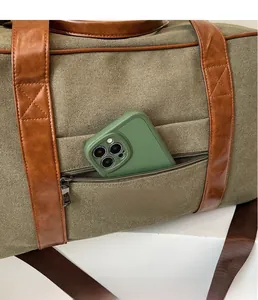 Close-up of olive canvas travel bag with leather accents showing front zipper pocket storage
