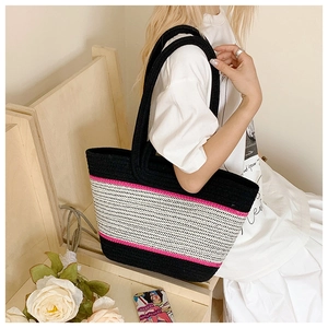 Detail of hand-woven large tote bag with contrast pink and black stripes on model