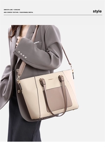 Detail of color-block tote bag with metal bar trim and adjustable shoulder strap on model