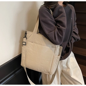 Detail view of beige canvas tote bag with shoulder straps and functional side pockets