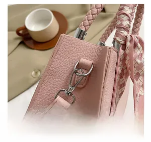 Detailed view of pink lychee leather bag with metal hook and scarf wrapped handle