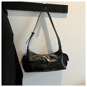 Close-up of black glossy patent leather crescent bag with decorative buckle and side pockets