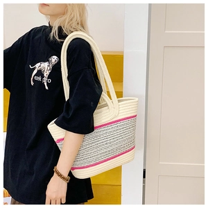 Detailed view of woven tote bag showing pink contrast stripes and rope shoulder straps