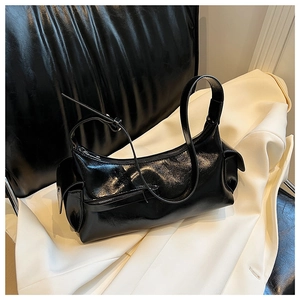 Detailed view of black patent leather baguette bag with silver zippers and side pockets