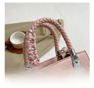Close-up of pink lychee leather bag with woven handle and checkered silk scarf detail