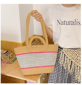 Detail of hand-woven straw tote with pink stripes and dual handle design