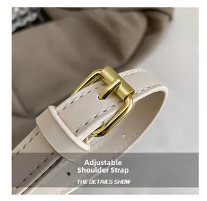 Close-up of adjustable cream leather shoulder strap with gold metal buckle detail