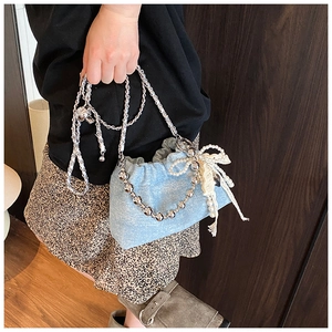Close-up of light blue sequin bucket bag with lace bow and pearl chain details