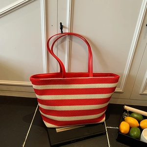 Large red and cream striped woven tote bag with leather handles in a trapezoid shape