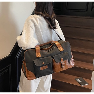 Detail of travel canvas bag showing leather strap handles and front retro style pockets