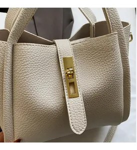 Close-up of cream textured leather handbag with a premium gold-toned twist lock closure
