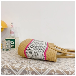 Detail of woven straw tote bag with pink stripes and grid pattern on lace tablecloth