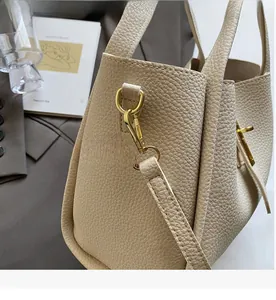 Close-up of golden hardware on beige lychee leather handbag with luxury texture