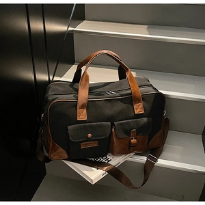 Detail of multi-pocket canvas travel bag with premium brown leather trim and metal buckles