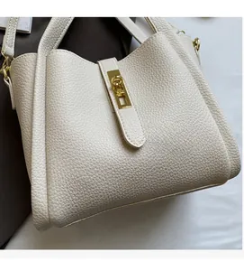 Close-up of pebble grain cowhide texture and gold metal buckle on beige bucket bag