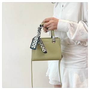 Close-up of light green lychee pattern handbag with checkered scarf and silver hardware