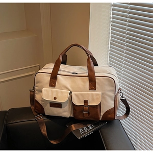 Close-up of canvas travel bag featuring brown leather pockets and durable metal buckles