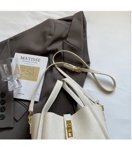 Detail of white litchi pattern leather bucket bag with gold lock and adjustable strap
