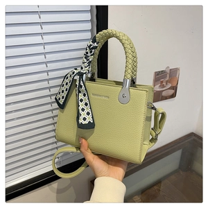 Detail of light green litchi grain handbag with woven handle and checkered silk scarf