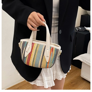 Detail of colorful woven straw tote with white leather handles and metallic strap rings