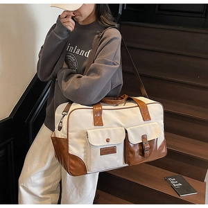 Detail of canvas travel bag with contrast PU leather pockets and metal hardware accents