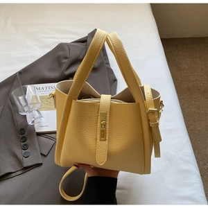 Close-up of yellow lychee pattern leather bucket bag with gold lock and metal hardware
