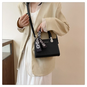 Detail of black litchi grain leather bag with a stylish black and white checkered scarf