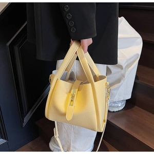 Detail of yellow lychee leather tote bag with metal lock and adjustable shoulder strap