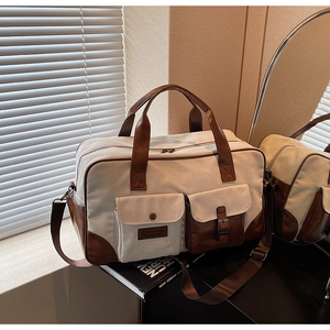 Detailed view of canvas travel bag with brown leather trim and dual front pockets